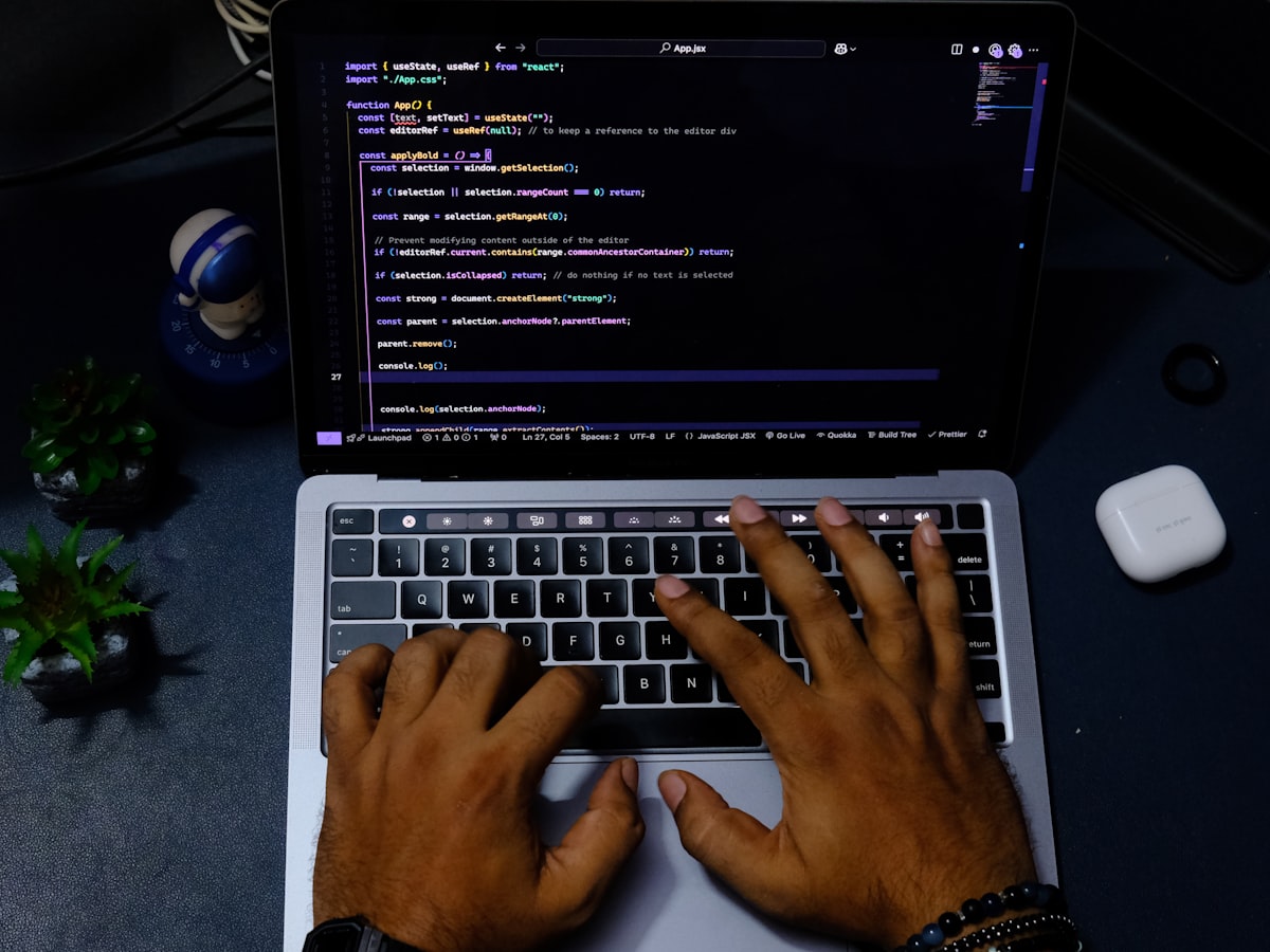 Hands typing code on a laptop keyboard